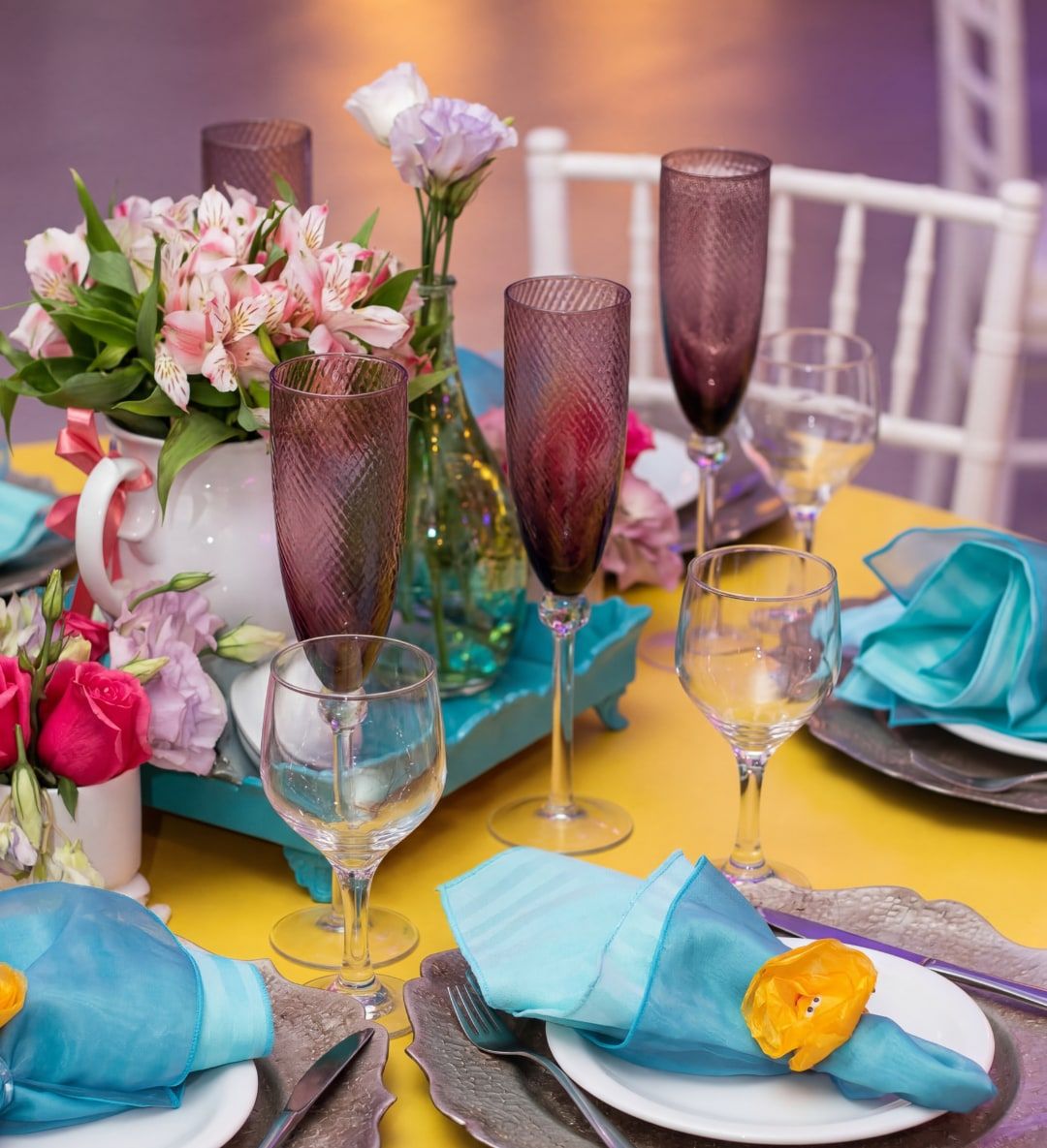 Mesa posta para festa de 15 anos com taças, flores e guardanapos azuis