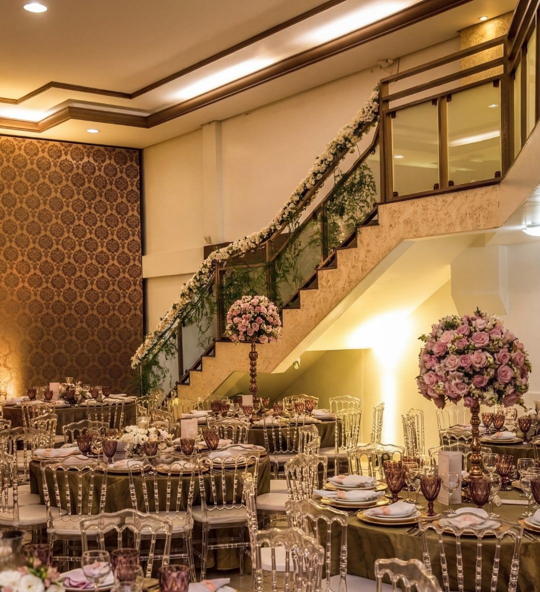 Salão com escada decorada com folhagens e mesas redondas