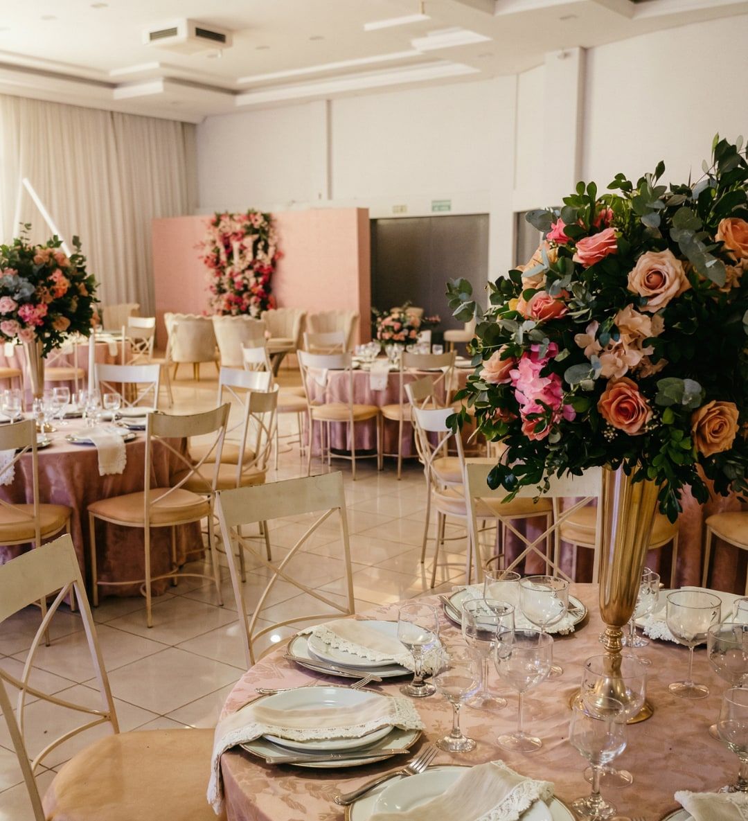 Salão montado para formatura com mesas redondas e arranjos de rosas