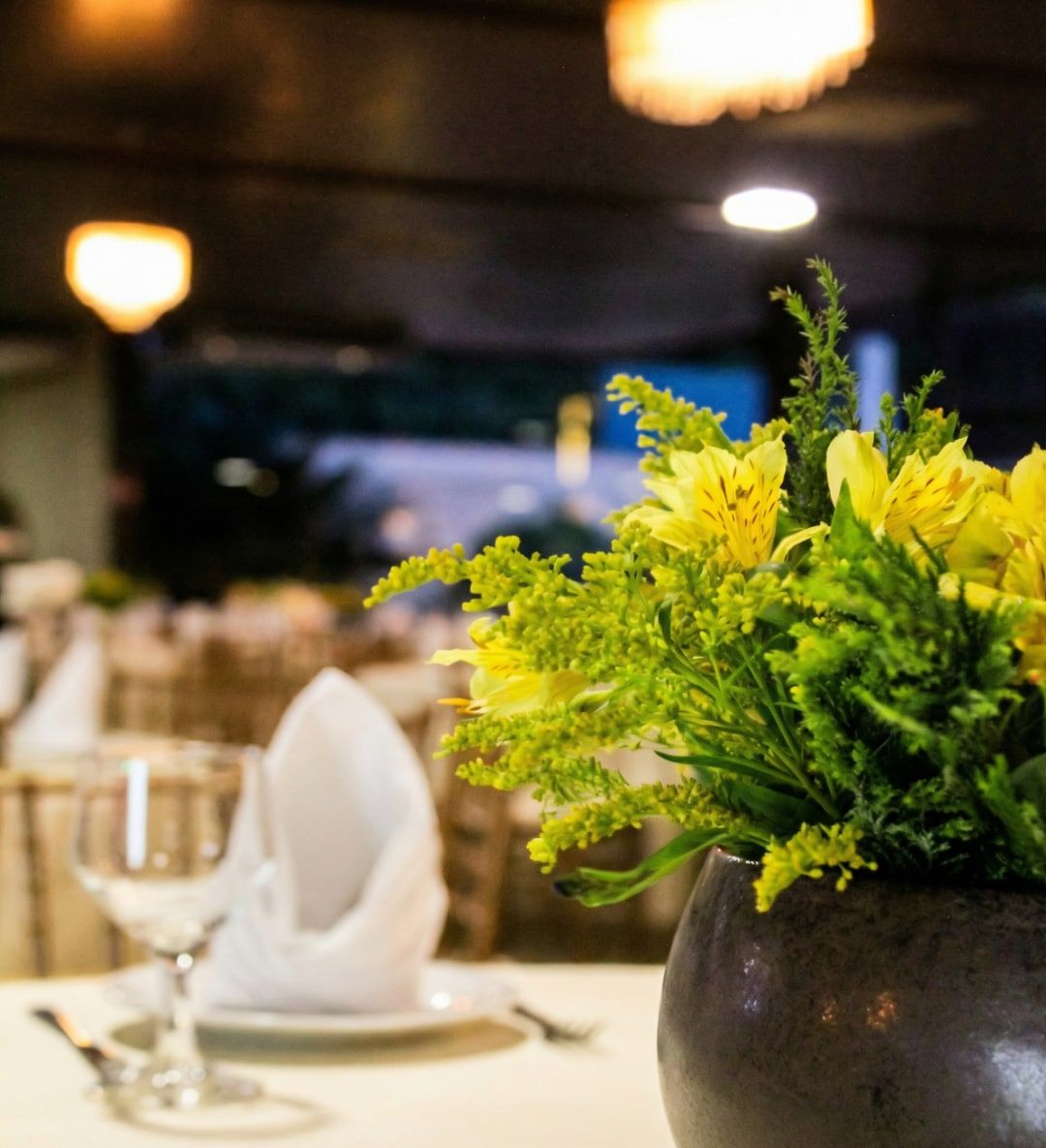 Mesa posta com arranjo de flores amarelas e guardanapo branco